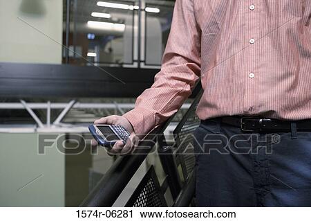 Mid section view of a person holding a hand held device View Large Photo Image Stock Image - Mid section view of a person holding a hand held device. Fotosearch