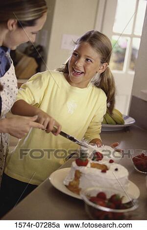 Stock Image - Mother and daughter icing a cake together. Fotosearch