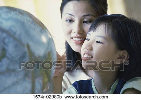 Mother and her daughter looking at a globe View Large Photo Image Stock Image - Mother and her daughter looking at a globe. Fotosearch