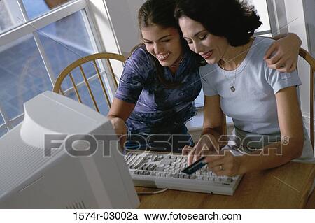 Mother and her daughter sitting in front of a computer View Large Photo Image Stock Image - Mother and her daughter sitting in front of a computer. Fotosearch