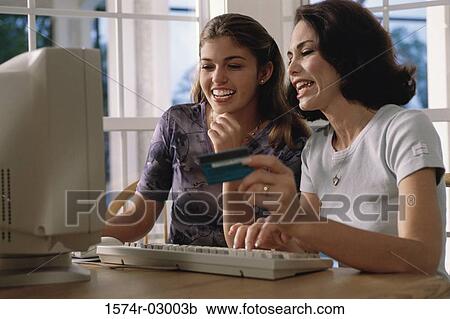 Mother and her daughter sitting in front of a computer View Large Photo Image Stock Image - Mother and her daughter sitting in front of a computer. Fotosearch