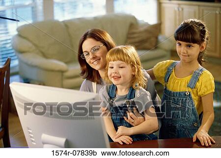 Mother and her two daughters in front of a computer monitor View Large Photo Image Stock Image - Mother and her two daughters in front of a computer monitor. Fotosearch
