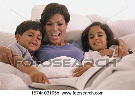 Stock Image - Mother lying in bed with her son and daughter. Fotosearch