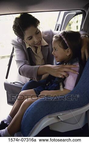 Mother placing her daughter in a car seat View Large Photo Image Stock Image - Mother placing her daughter in a car seat. Fotosearch