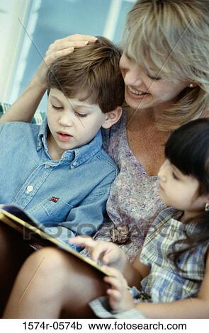 Stock Image - Mother reading a book with her son and daughter. Fotosearch