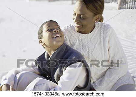 Stock Image - Mother sitting with her son on the beach. Fotosearch