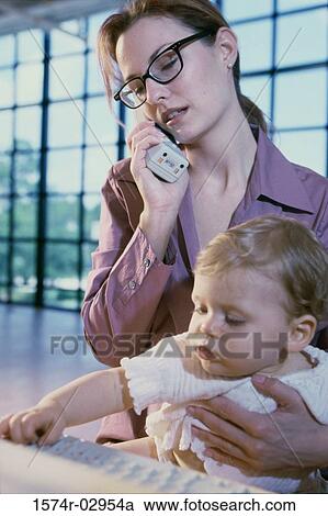 Mother talking on a telephone holding her baby girl View Large Photo Image Stock Image - Mother talking on a telephone holding her baby girl. Fotosearch
