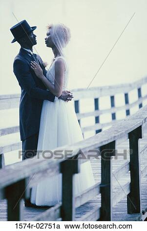 Newlywed couple embracing each other on a pier View Large Photo Image Stock Image - Newlywed couple embracing each other on a pier. Fotosearch