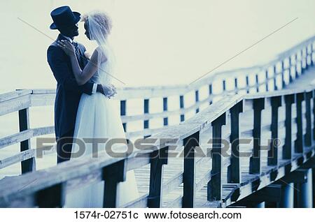 Stock Image - Newlywed couple embracing each other on a pier. Fotosearch
