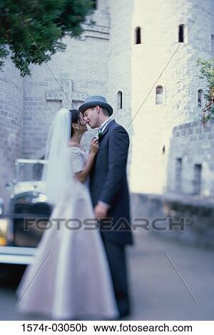 Newlywed couple kissing each other in front of an antique car View Large Photo Image Stock Image - Newlywed couple kissing each other in front of an antique car. Fotosearch