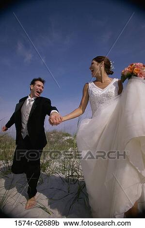 Newlywed couple running on sand View Large Photo Image Stock Image - Newlywed couple running on sand. Fotosearch