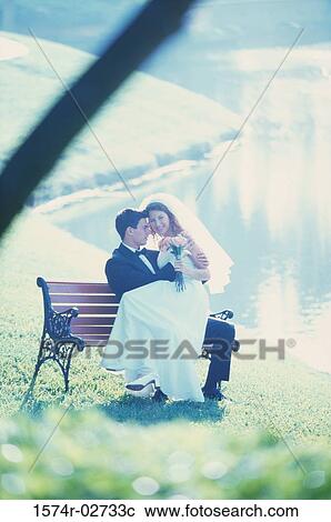 Newlywed couple sitting on a park bench View Large Photo Image Stock Image - Newlywed couple sitting on a park bench. Fotosearch