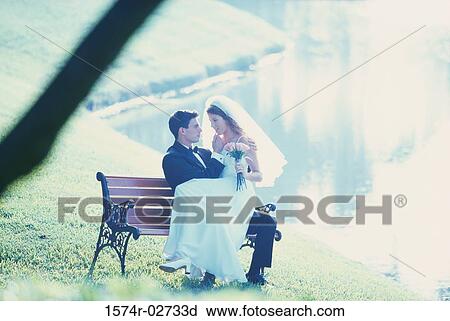 Newlywed couple sitting on a park bench View Large Photo Image Stock Image - Newlywed couple sitting on a park bench. Fotosearch