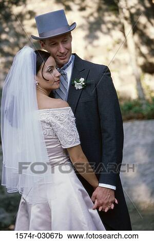 Stock Image - Newlywed couple standing holding hands. Fotosearch