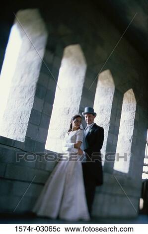 Stock Image - Newlywed couple standing in a castle. Fotosearch