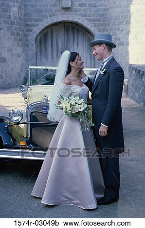 Newlywed couple standing in front of an antique car View Large Photo Image Stock Image - Newlywed couple standing in front of an antique car. Fotosearch