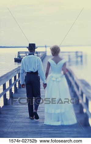 Stock Image - Newlywed couple walking on a pier. Fotosearch