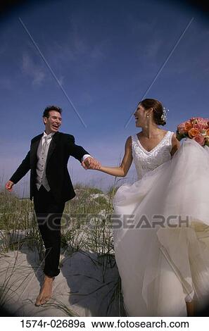 Newlywed couple walking on sand View Large Photo Image Stock Image - Newlywed couple walking on sand. Fotosearch
