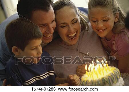 Parents and their two children celebrating a birthday with a cake View Large Photo Image Stock Image - Parents and their two children celebrating a birthday with a cake. Fotosearch