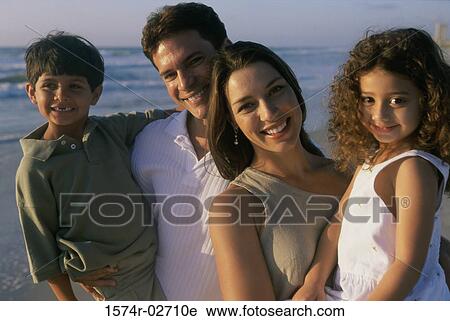 Stock Image - Parents holding their son and daughter on the beach. Fotosearch
