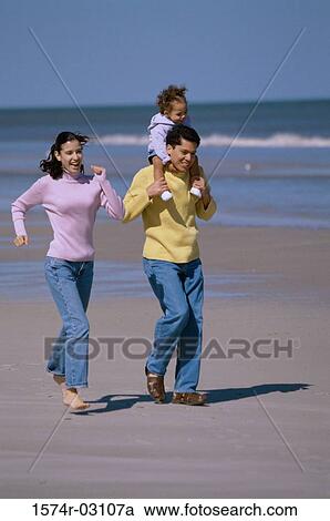Stock Image - Parents playing with their daughter on the beach. Fotosearch