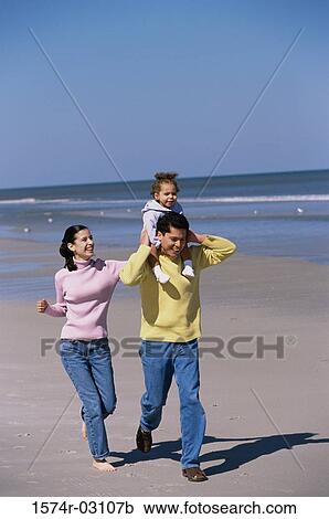 Stock Image - Parents playing with their daughter on the beach. Fotosearch