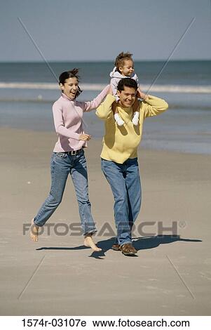 Stock Image - Parents playing with their daughter on the beach. Fotosearch