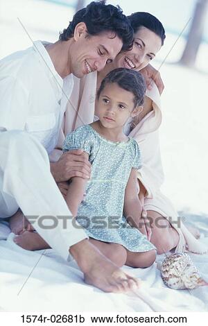 Parents sitting with their daughter on the beach View Large Photo Image Stock Image - Parents sitting with their daughter on the beach. Fotosearch