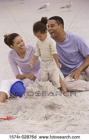 Stock Image - Parents with their daughter on the beach. Fotosearch