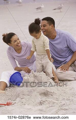 Stock Image - Parents with their daughter on the beach. Fotosearch