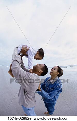 Stock Image - Parents with their daughter on the beach. Fotosearch