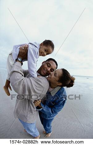 Stock Image - Parents with their daughter on the beach. Fotosearch