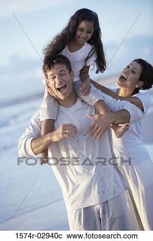 Stock Image - Parents with their daughter on the beach. Fotosearch