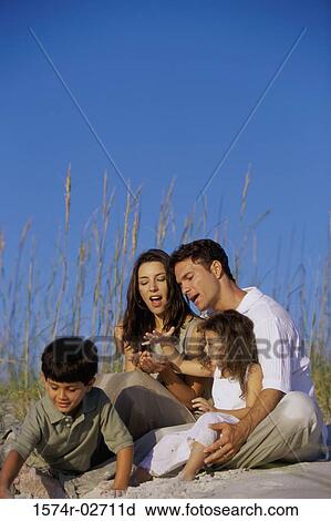 Stock Image - Parents with their son and daughter on the beach. Fotosearch
