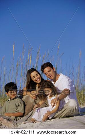 Stock Image - Parents with their son and daughter on the beach. Fotosearch
