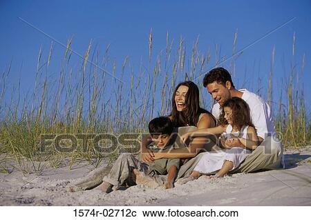 Stock Image - Parents with their son and daughter on the beach. Fotosearch
