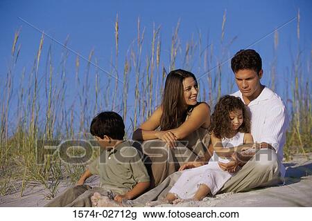 Stock Image - Parents with their son and daughter on the beach. Fotosearch