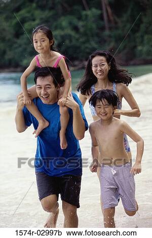 Stock Image - Parents with their son and daughter on the beach. Fotosearch