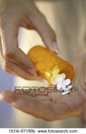 Stock Image - Person holding a vial of tablets. Fotosearch