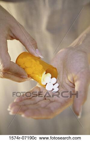 Stock Image - Person holding a vial of tablets. Fotosearch