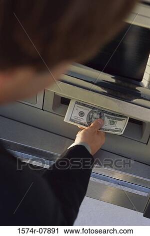 Stock Image - Person withdrawing cash from an ATM. Fotosearch