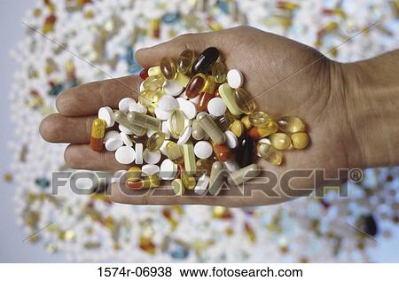 Stock Photo - Person's hand holding an assortment of tablets and capsules. Fotosearch