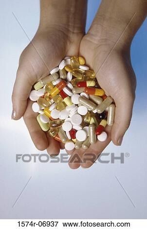 Stock Photo - Person's hands holding an assortment of tablets and capsules. Fotosearch