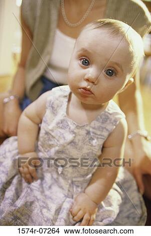 Picture - Portrait of a baby girl sitting with her mother behind her. Fotosearch