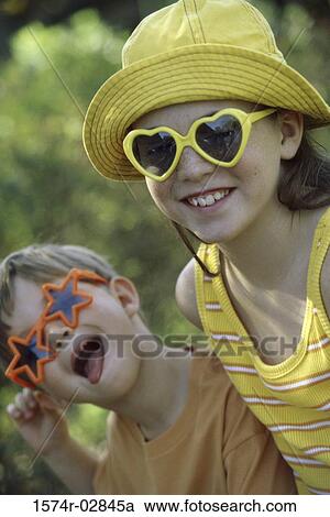 Stock Image - Portrait of a boy and a girl wearing sunglasses making a face. Fotosearch