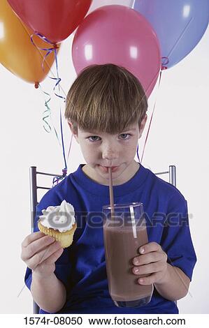 Stock Image - Portrait of a boy drinking from a glass through a drinking straw. Fotosearch