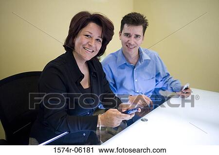Portrait of a businessman and a businesswoman sitting in an office View Large Photo Image Stock Image - Portrait of a businessman and a businesswoman sitting in an office. Fotosearch