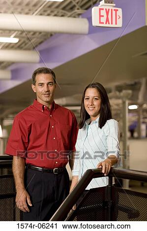 Stock Image - Portrait of a businessman and a businesswoman standing on stairs. Fotosearch