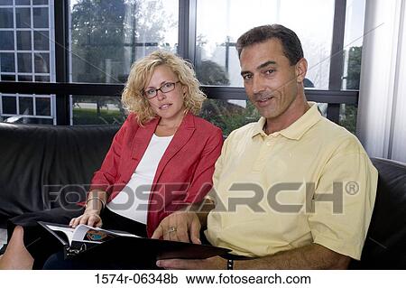 Stock Image - Portrait of a businessman and a businesswoman smiling in an office. Fotosearch