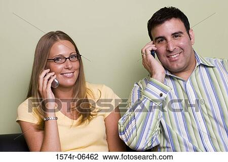 Stock Image - Portrait of a businessman and a businesswoman talking on mobile phones. Fotosearch